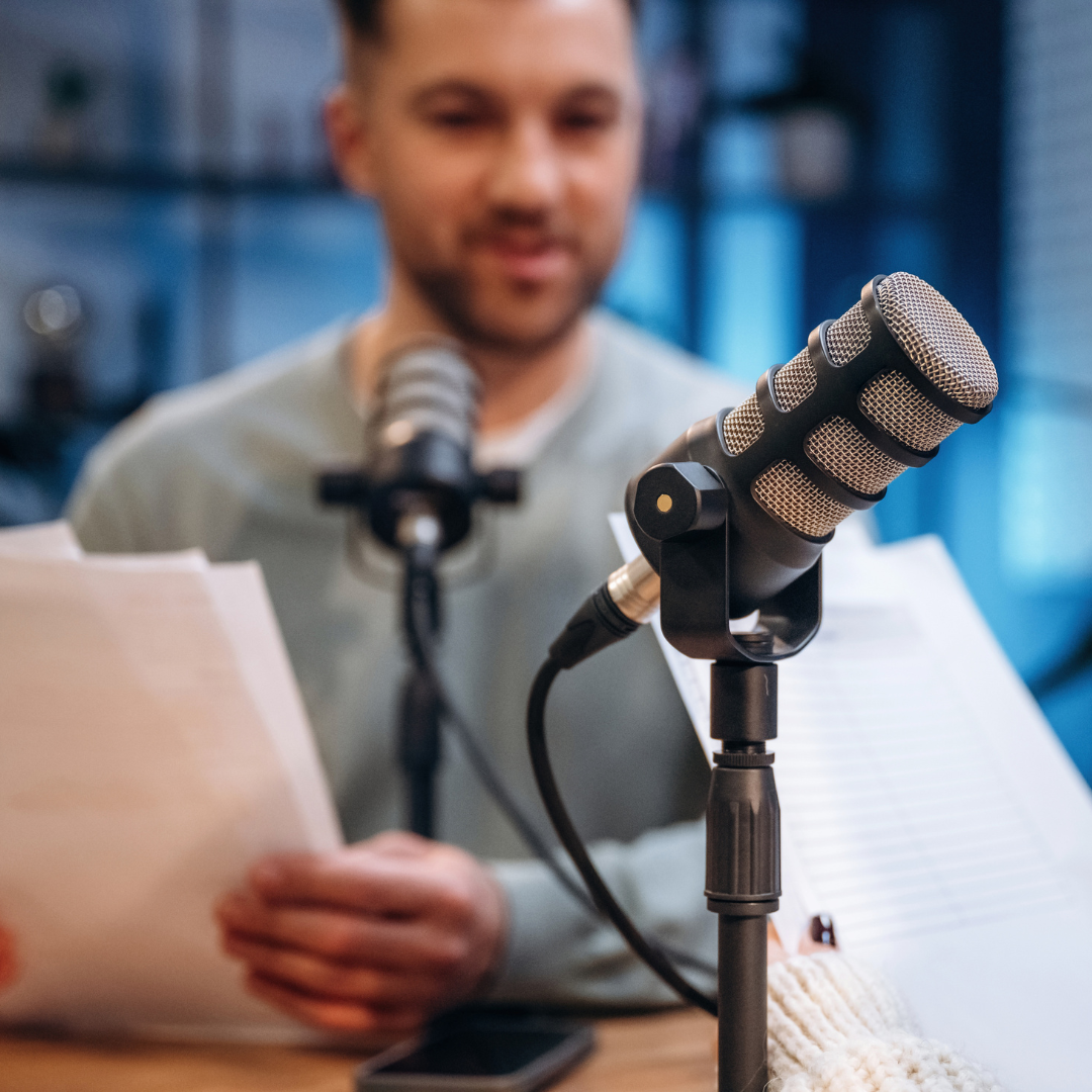 Author being interviewed on a podcast, microphone in foreground, book cover visible in background.