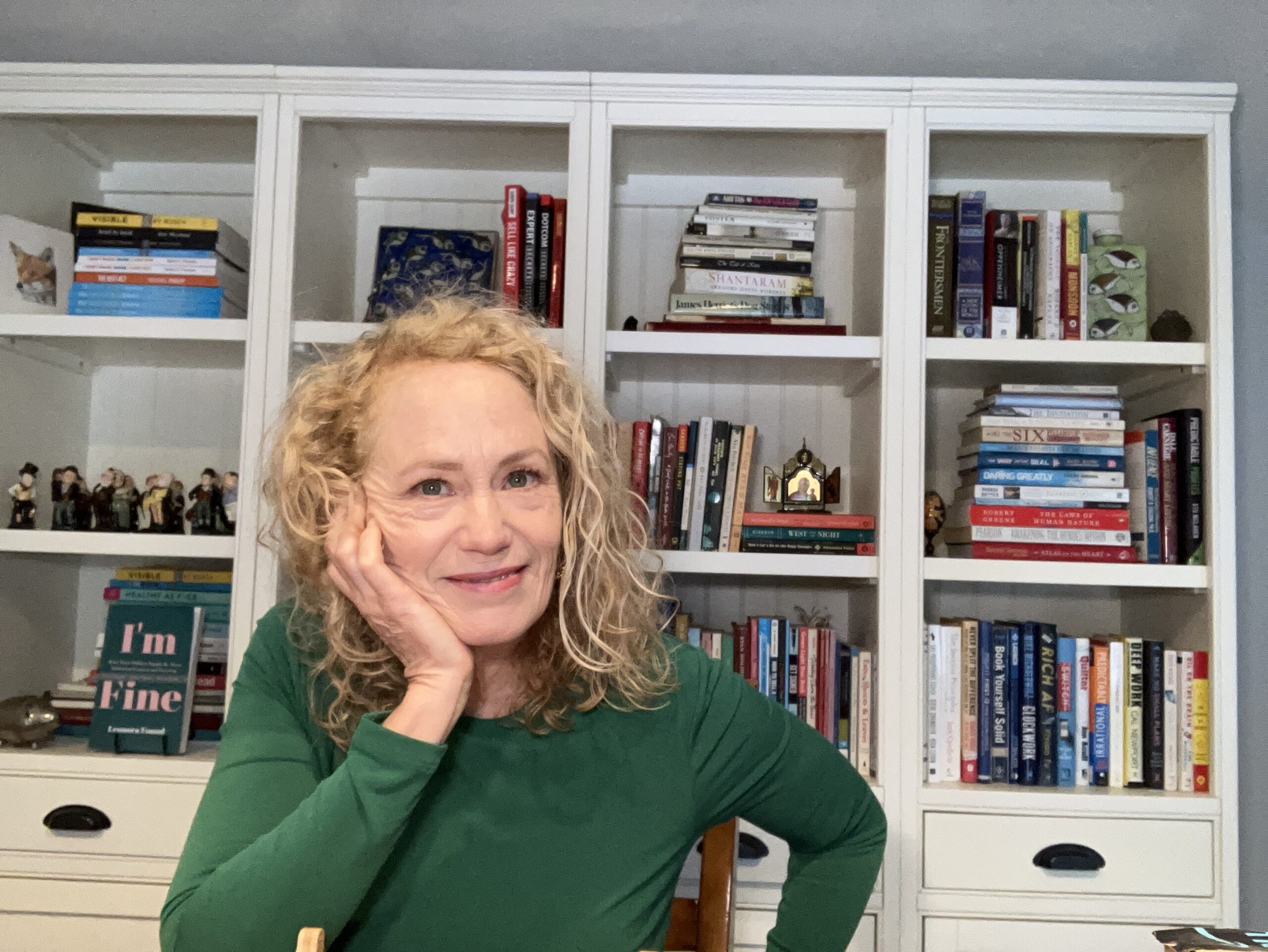 Photo of Ann Sheybani, book coach, in front of books symbolizing the authority that comes in authorship